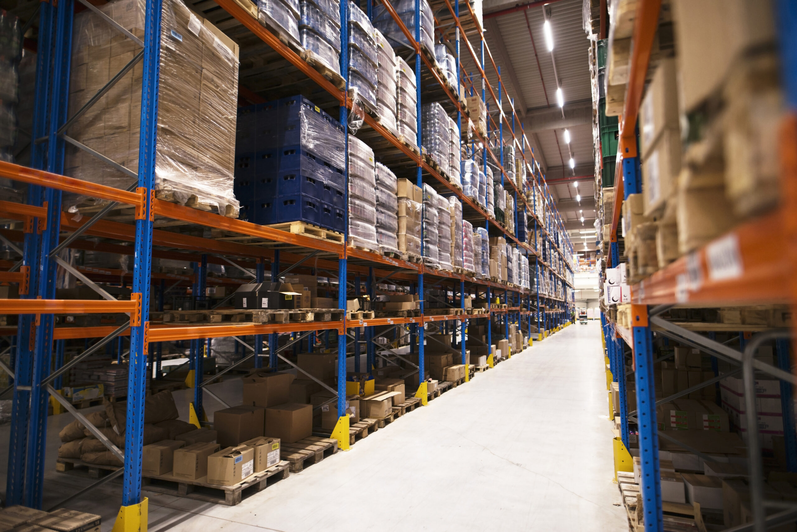 Interior of large distribution warehouse with shelves stacked with palettes and goods ready for the market